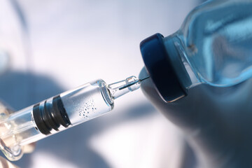 Doctor filling syringe with vaccine from vial, closeup