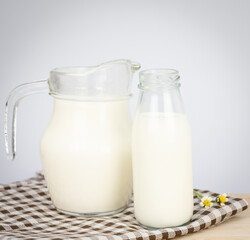 A jug and bottle of milk glass on a wooden table on background..Raw milk is high in calcium and protein to drink for all ages..Milk consumption nutritious and healthy dairy products concept..