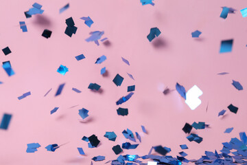 Shiny blue confetti falling down on pink background