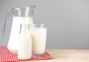  A jug and bottle of milk glass on a wooden table on background..Raw milk is high in calcium and protein to drink for all ages..Milk consumption nutritious and healthy dairy products concept..