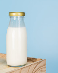  Bottles with fresh milk on a wooden table on a blue background..Raw milk is high in calcium and protein to drink for all ages..Milk consumption nutritious and healthy dairy products concept.