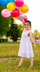 girls playing with balloons on the grass and in a field of flowers on a sunny day enjoying and smiling
