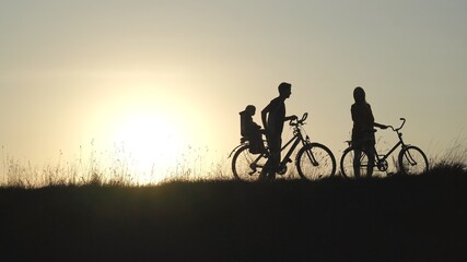 Fototapeta na wymiar Friendly family with a child on bicycles during sunset.