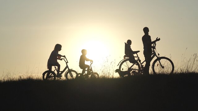 Silhouettes of a large large family with bicycles and dogs at sunset.