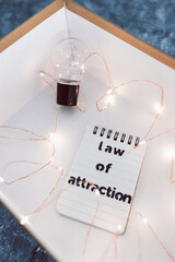 law of attraction and positive mindset, box as metaphor of the mind with Law Of Attraction notepad and light bulb surrounded by fairy lights