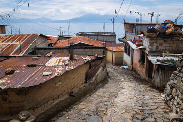 Fototapeta na wymiar Street along local houses with rusty tin roofs in mountain village along lake Atitlan, Santa Cruz la Laguna, Guatemala