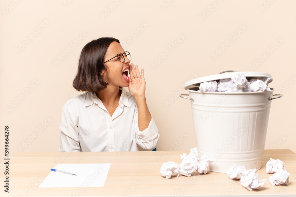 Sticker young latin woman yelling loudly and angrily to copy space on the side, with hand next to mouth