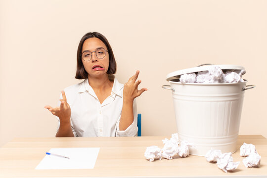 young latin woman shrugging with a dumb, crazy, confused, puzzled expression, feeling annoyed and clueless