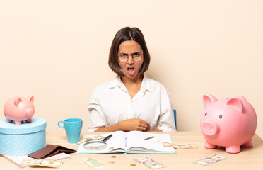 young latin woman looking shocked, angry, annoyed or disappointed, open mouthed and furious