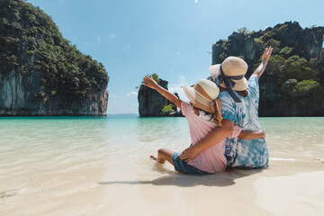 Asian mother and child girl sitting on the beach and enjoying with beautiful nature together in...