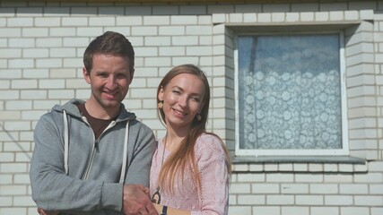 Young happy spouses on the background of their home.