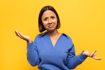 young latin woman looking puzzled, confused and stressed, wondering between different options,...