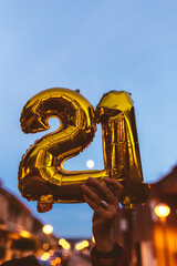 Celebrating with Gold foil balloons numeral 21 at night. Happy New year 2021 celebration.