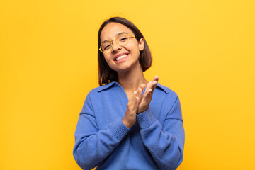 young latin woman feeling happy and successful, smiling and clapping hands, saying congratulations...