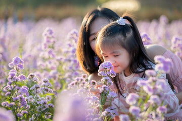 Obraz na płótnie Canvas Cute asian child girl and her mother enjoying with beautiful flower with fun together in the flower garden.