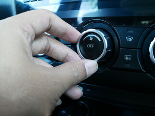hand turning on air conditioning system in a car.