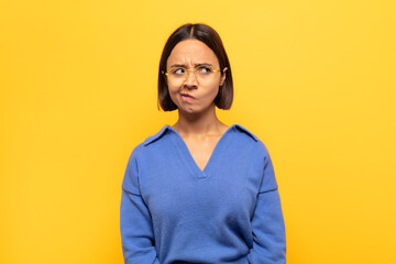 young latin woman looking puzzled and confused, wondering or trying to solve a problem or thinking