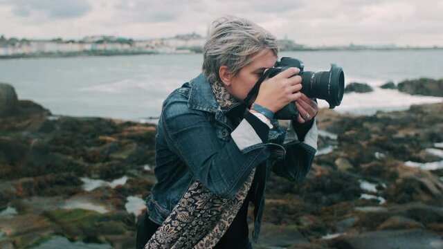 Woman taking pictures by the ocean