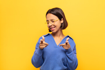 young latin woman smiling with a positive, successful, happy attitude pointing to the camera,...