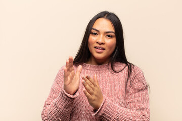 young latin woman feeling happy and successful, smiling and clapping hands, saying congratulations...