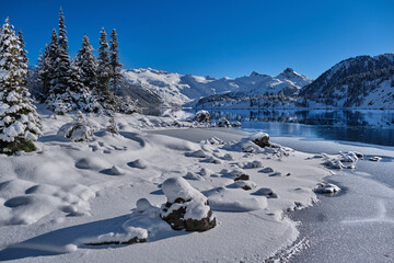 Frozen mountain lake with blue ice and  fresh fluffy snow on rocks.  Garibladi Lake near Whistler. British Columbia. Canada 