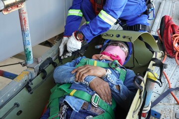 Injured workers encapsulate by sked stretcher to take off scaffolding in working at heights and...