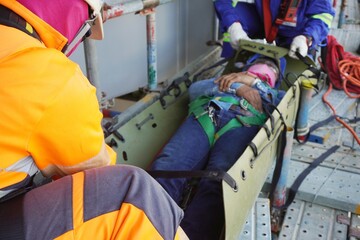 Rescuers during encapsulate injured workers by sked stretcher to take off scaffolding in working at heights and transfer them to the field medical team as part of emergency drills at a chemical plant 