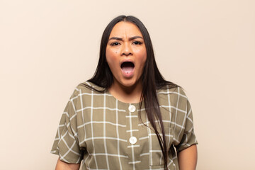 young latin woman feeling terrified and shocked, with mouth wide open in surprise
