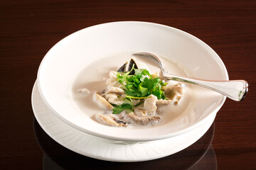 Thai coconut milk soup in a white bowl on a dark wooden table with copy space