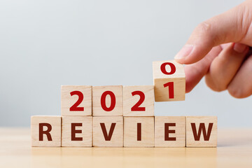 2021 review concept. Hand flip wood cube change year 2020 to 2021 and the word REVIEW on wooden...