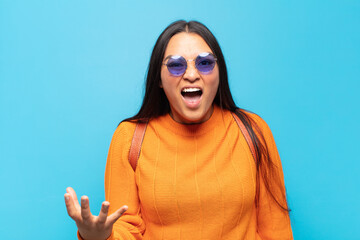 young latin woman looking angry, annoyed and frustrated screaming wtf or what’s wrong with you