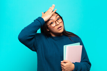 young latin woman raising palm to forehead thinking oops, after making a stupid mistake or...