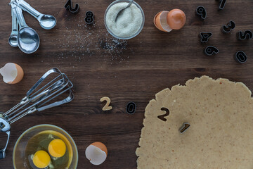 Top down view of a baking scene with baking utensils, ingredients and number cookie cutters using 2021. 