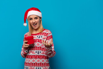 blonde woman with santa hat looking angry, annoyed and frustrated screaming wtf or what’s wrong...