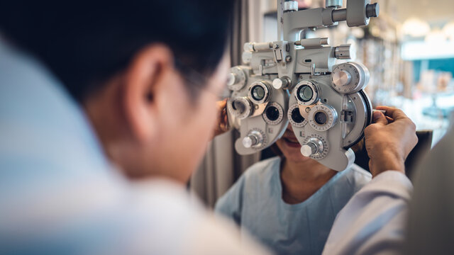 optometrist using phoropter to check eyesight value for client eyeglasses