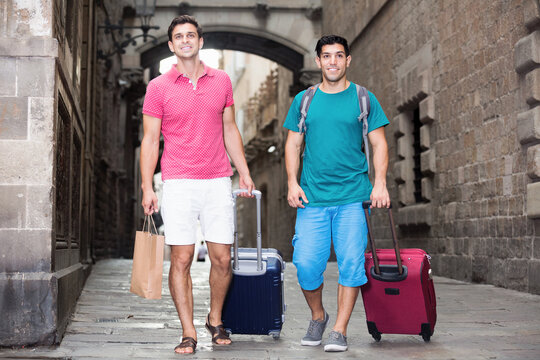 Two men are walking to culture center with baggage and map in Barcelona