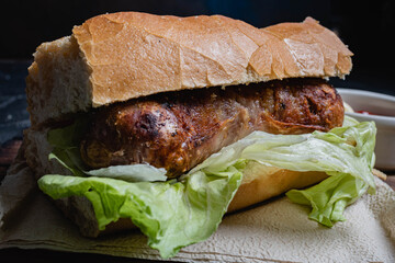 primer plano de choripan comida tipica y tradicional de argentina sandwich de pan con chorizo de cerdo con condimentos salsa criolla lechuga cebolla pimiento morron tomate mayonesa kechup y moztaza