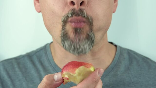 Close-up, a man with beard and moustache eating a red apple, close-up, 4K