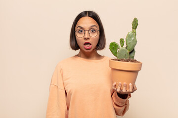 young latin woman looking very shocked or surprised, staring with open mouth saying wow