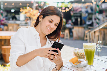 Woman using her phone and eating in a restaurant.