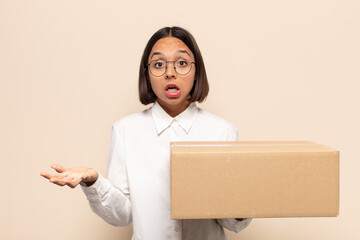 young latin woman open-mouthed and amazed, shocked and astonished with an unbelievable surprise