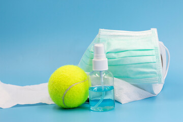 Tennis Covid prevention with face mask, hand sanitizer, tissue paper on blue background