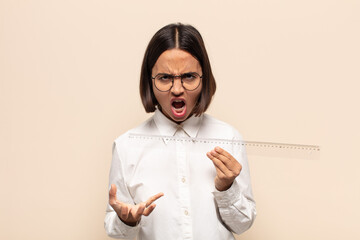 young latin woman looking angry, annoyed and frustrated screaming wtf or what’s wrong with you