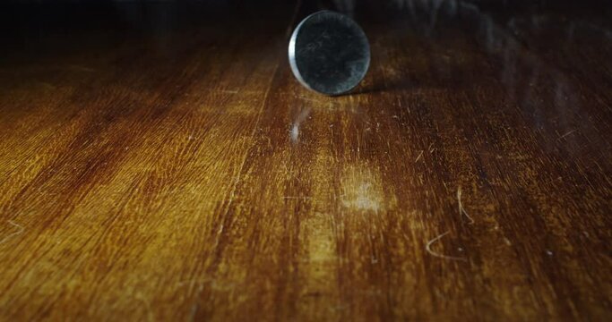 Closeup of coin flipping of wooden table, 10 cent Italian lira, static, slow