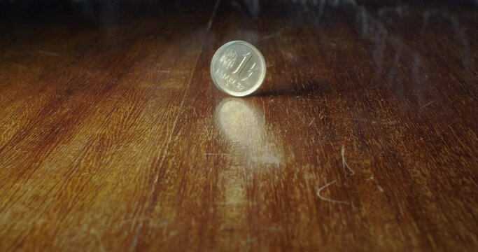 Closeup of 1 Spanish peseta flipping on wooden table, static, slow