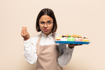 young latin woman making capice or money gesture, telling you to pay your debts!
