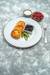 front view delicious sweet muffins with berries inside plate on a light background taste fruit photo pancake sugar dough