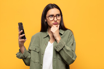young latin woman thinking, feeling doubtful and confused, with different options, wondering which...