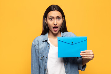 young latin woman looking very shocked or surprised, staring with open mouth saying wow