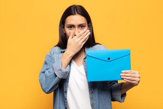 young latin woman covering mouth with hands with a shocked, surprised expression, keeping a secret or saying oops